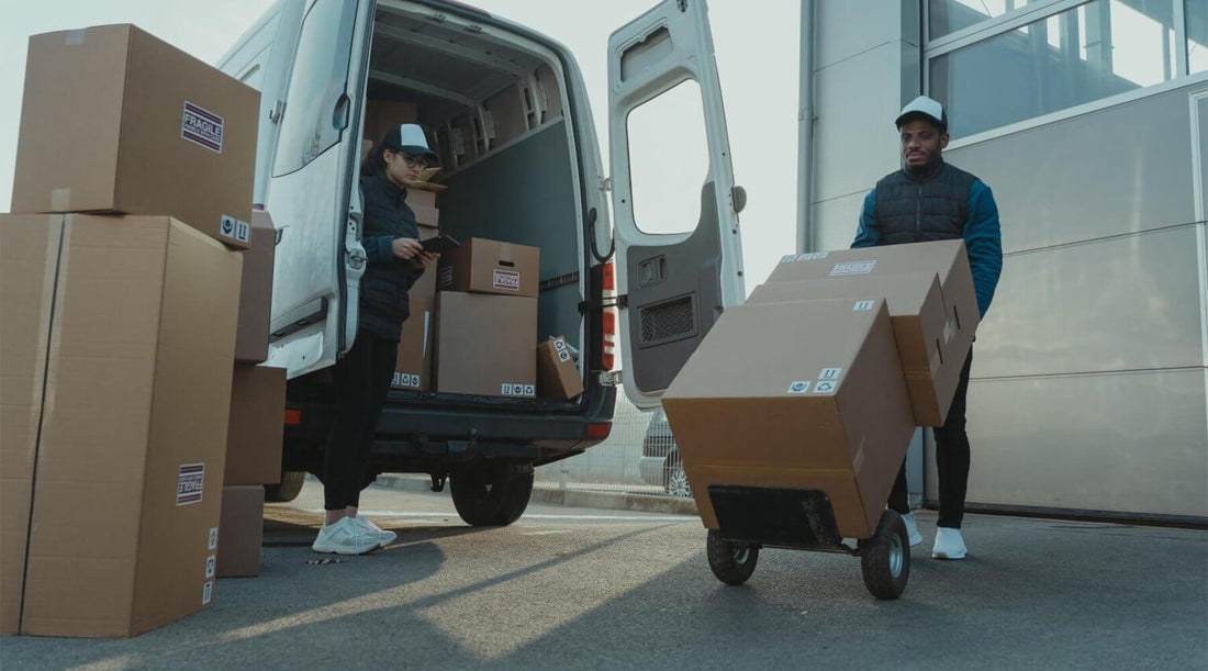 Delivery workers unloading packages from a van with large boxes on a dolly, showcasing efficient logistics and strategies for reducing shipping costs in e-commerce