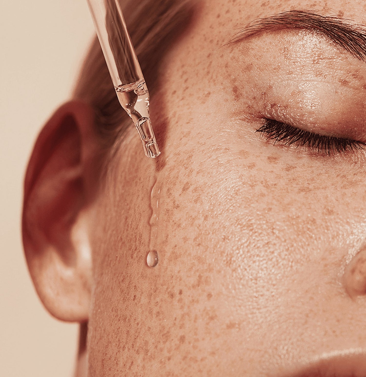 Female freckled face with serum drop.