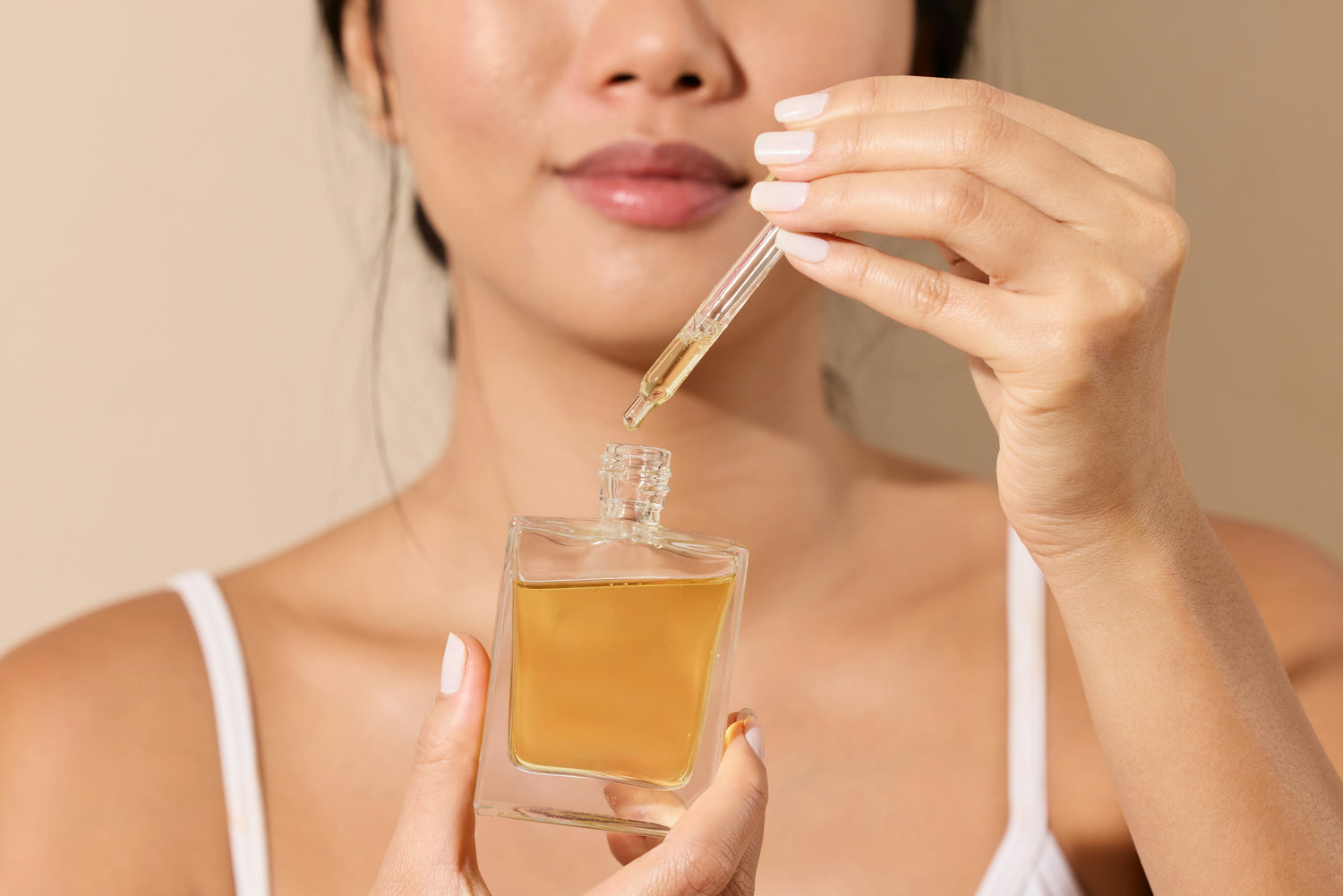 Female smiling with serum bottle.