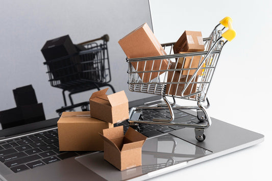 Image of laptop with a symbolic shopping cart on top with open and closed boxes in and around the shopping cart, symbolizing ecommerce