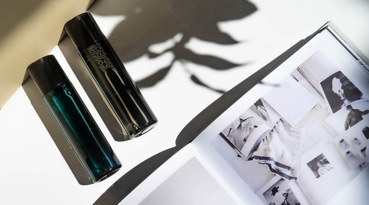 Minimalist composition featuring sleek black beauty product bottles and an open design book, accented by soft shadows, symbolizing elegance and creative inspiration in product branding