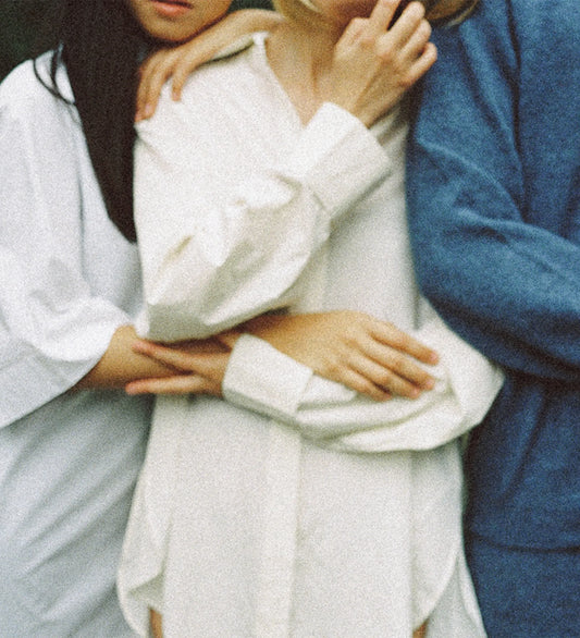 Close-up of three people standing close together, with their arms wrapped around each other in a gesture of support and belonging.