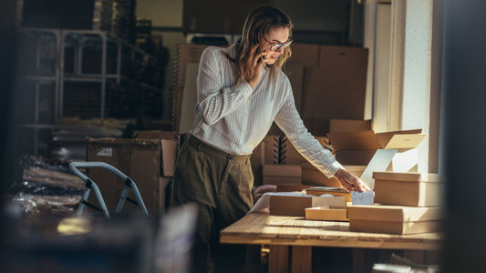  Entrepreneur packing products in a warehouse while on the phone, showcasing the multitasking nature of e-commerce business owners managing operations