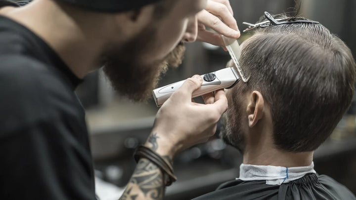 Barber using a trimmer to carefully style a client’s hair in a professional barbershop setting.