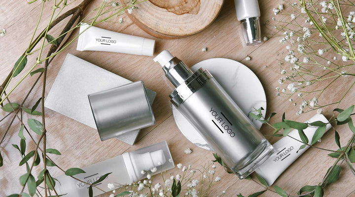  Elegant arrangement of customizable silver skincare bottles surrounded by greenery and natural elements, emphasizing luxury and eco-conscious beauty branding