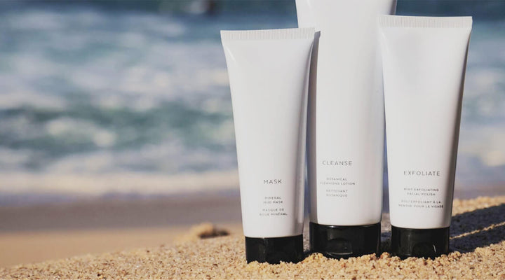  Minimalist skincare tubes labeled "Mask," "Cleanse," and "Exfoliate" displayed on sandy beach, embodying natural beauty and ocean-inspired branding