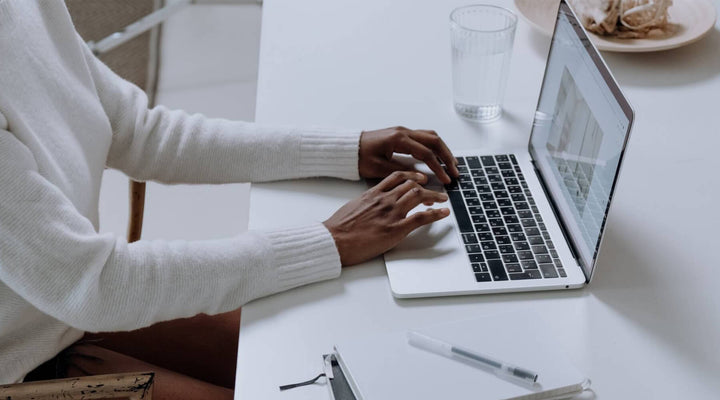  Close-up of a person typing on a laptop at a clean, minimalist desk, symbolizing productivity and focus in a modern work environment