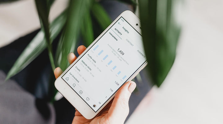 Close-up of a hand holding a smartphone displaying Instagram analytics, highlighting strategies for building a strong social media presence and growing brand engagement