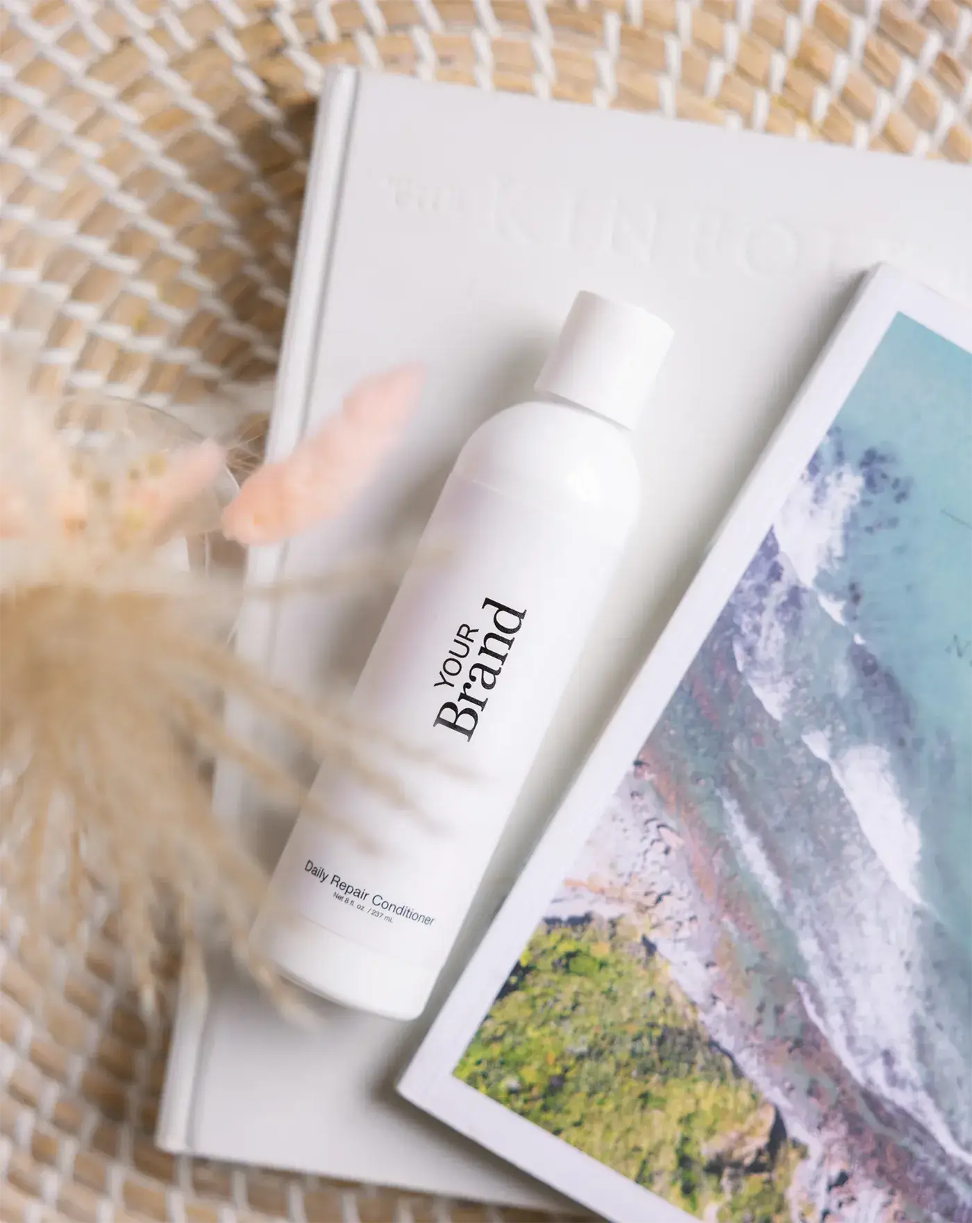 White conditioner bottle labeled 'Your Brand' on a magazine with a beach cover