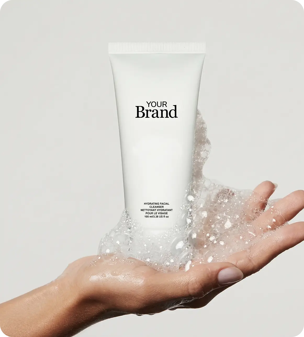 Hand holding a tube of skincare product with 'Your Brand' text on a light gray background