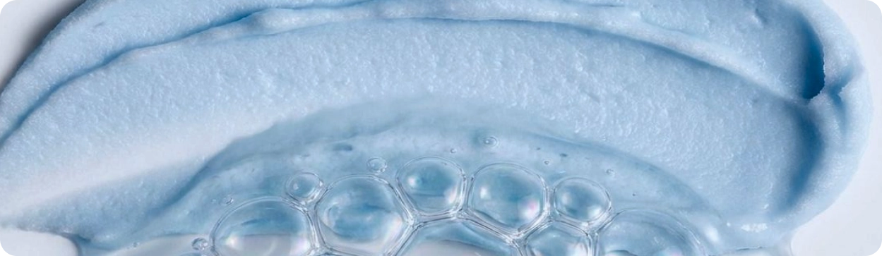 Close-up of blue cream with bubbles, likely from a skincare product.