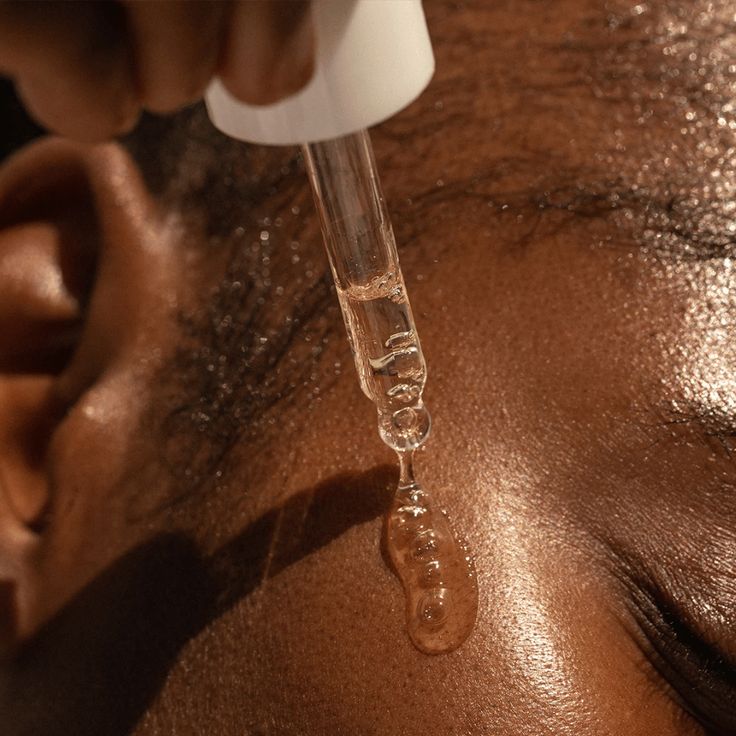 Dropper with a clear liquid being applied to skin