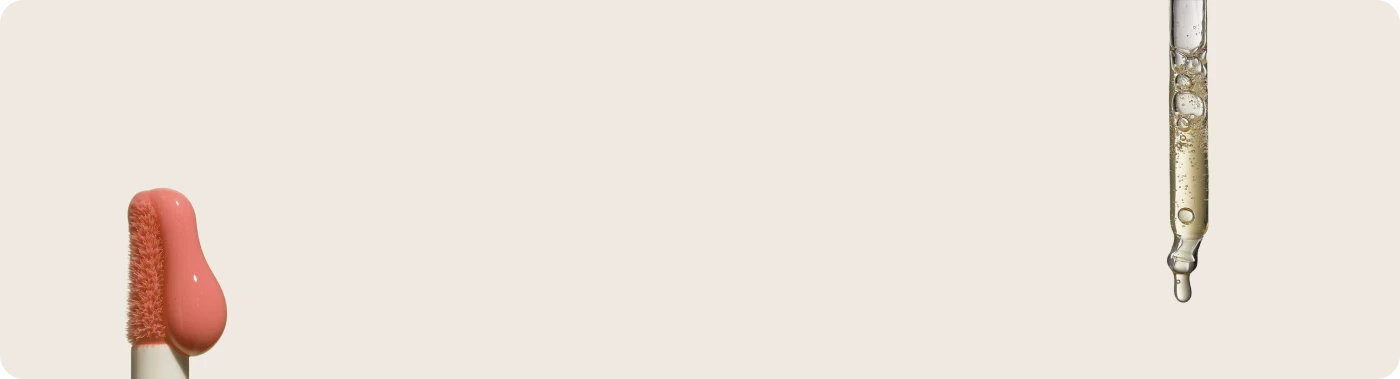 Cosmetic brush with red bristle tip and clear liquid dropper on a light beige background