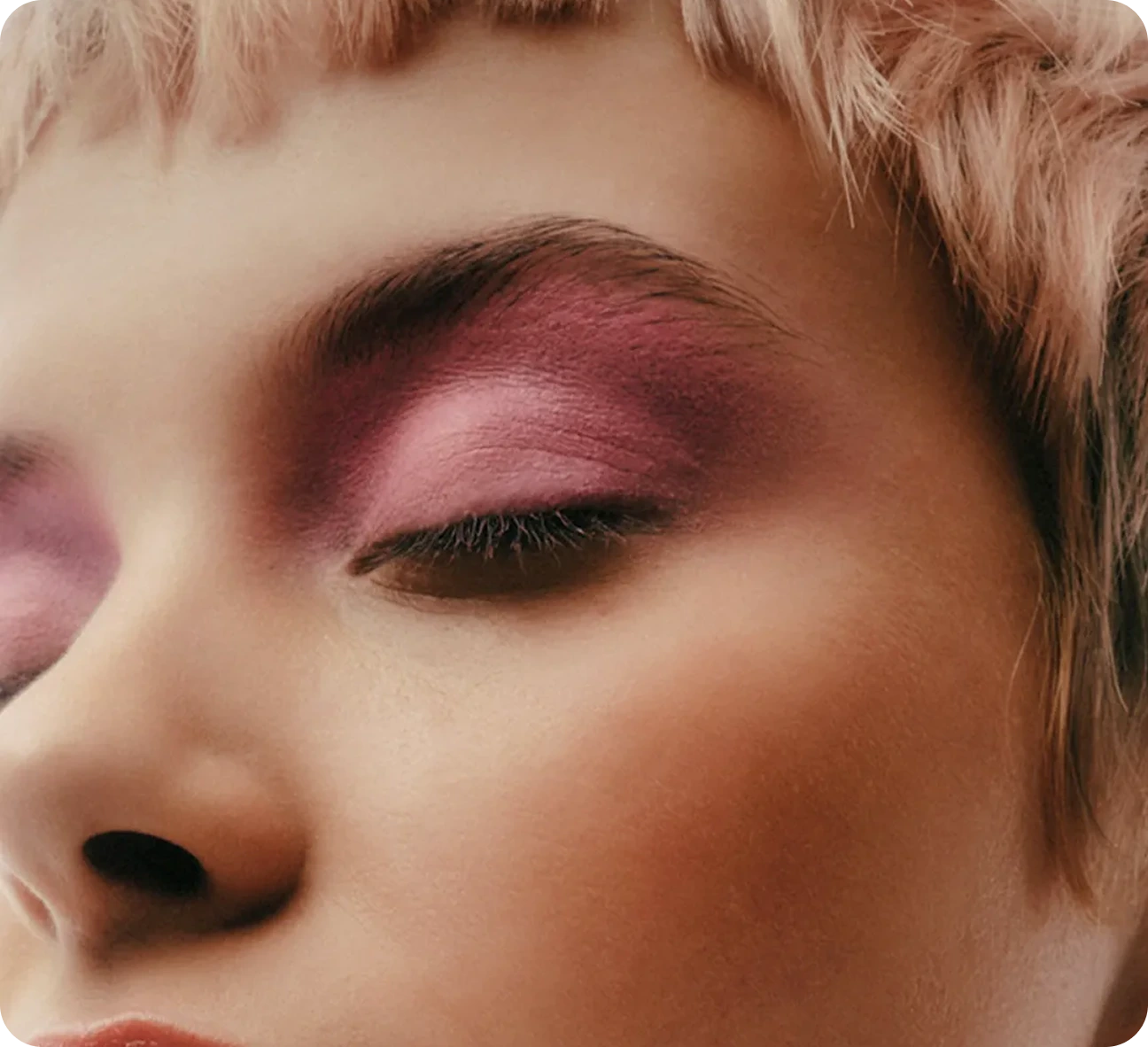 Close-up of makeup artist holding custom branded beauty product bottle near model's face