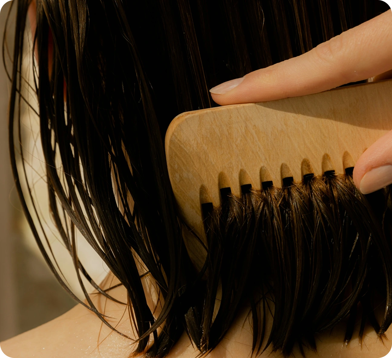 Hairstylist using professional paddle brush on long healthy hair with custom salon products