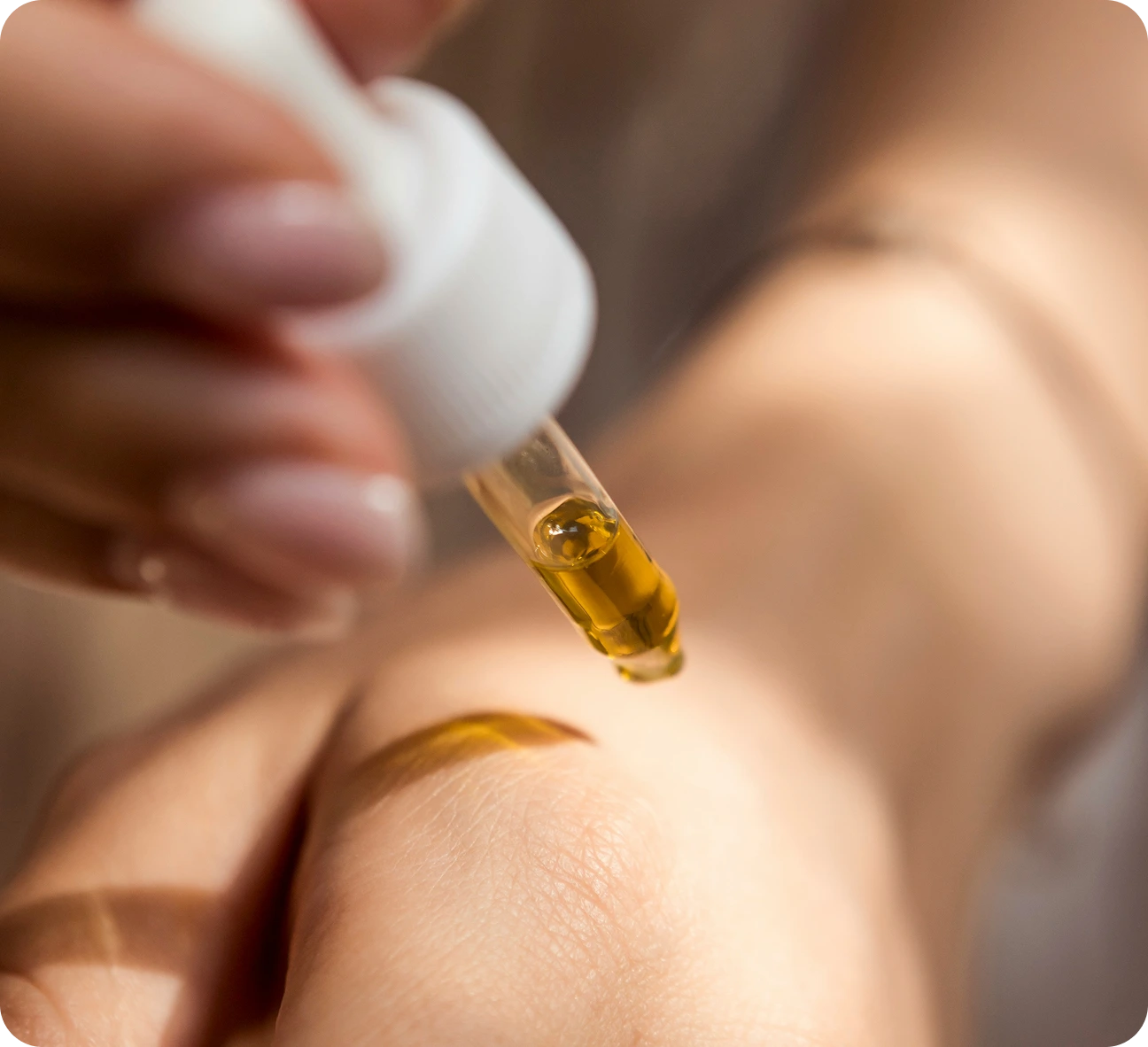 Hand applying golden facial oil serum to skin demonstrating custom skincare product