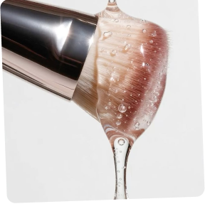 Makeup brush with water droplets on a white background