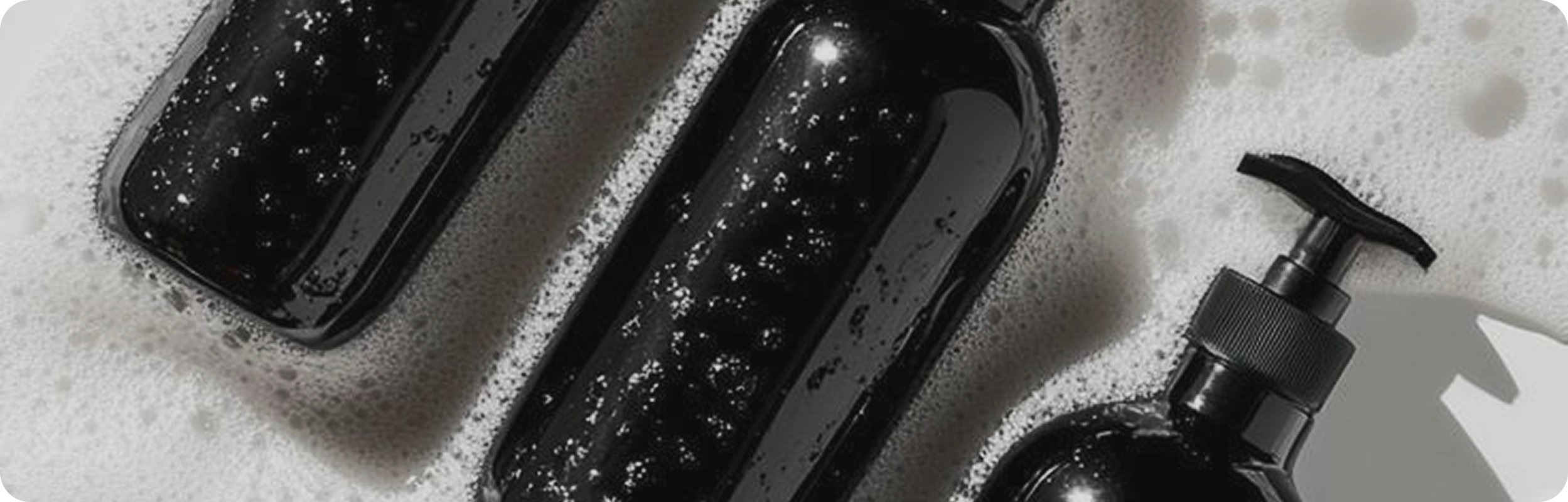Black soap dispenser and bottles with pump on a textured surface