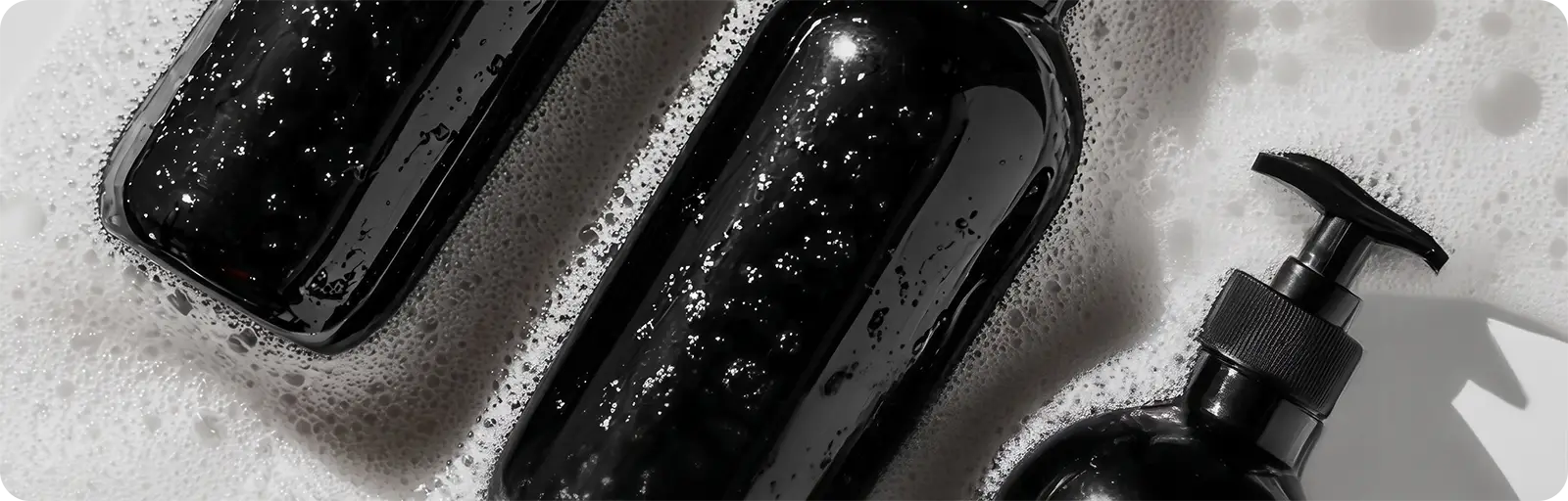 Black soap dispenser and bottles with pump on a textured surface