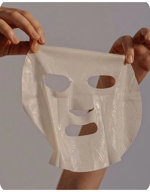 Sheet mask held by hands against a neutral background