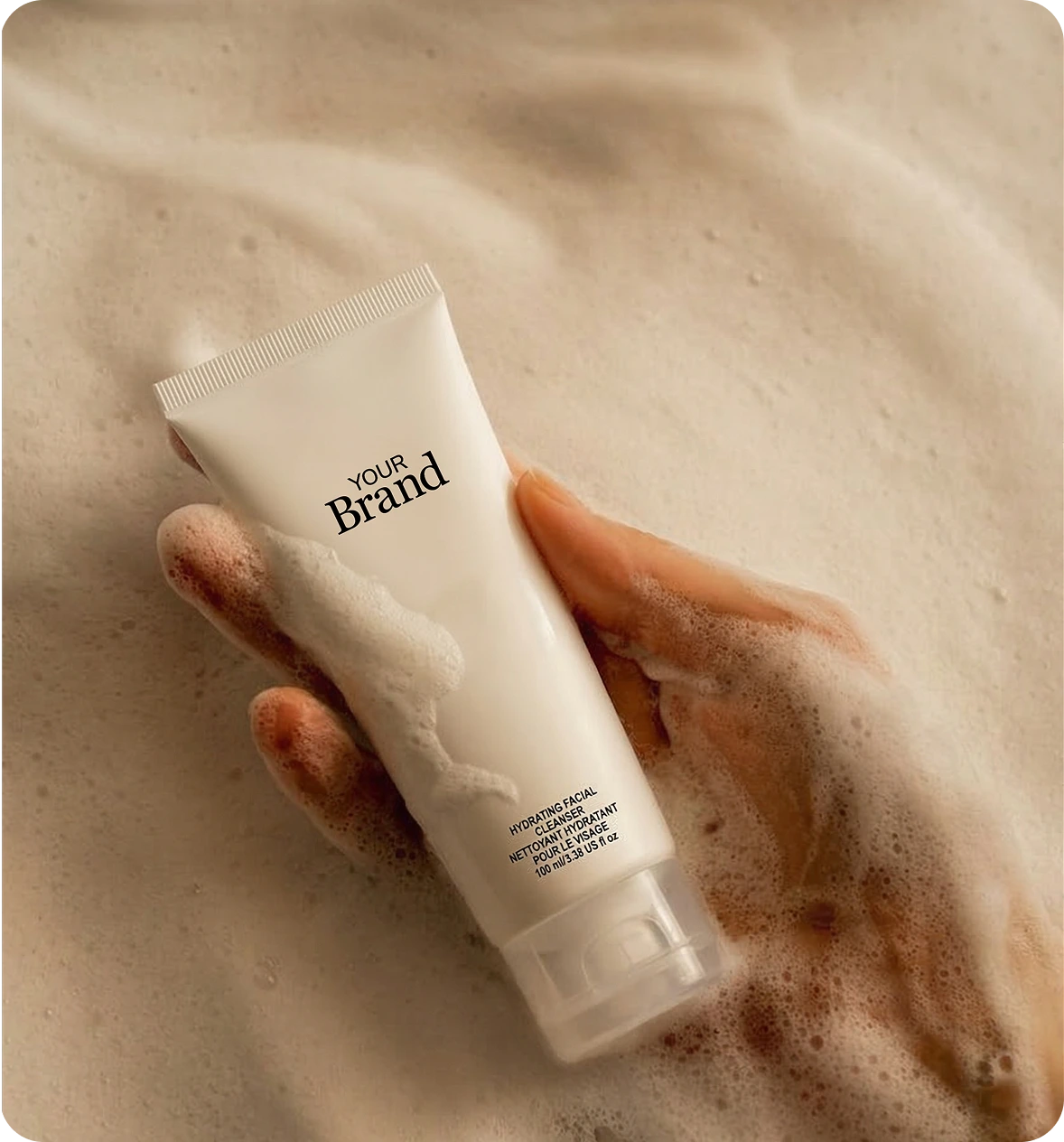 Hand holding a tube of cream with 'Your Brand' text on a beige background