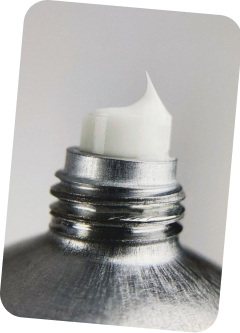 Close-up of a metal bottle cap with a white candle inside, on a light gray background.