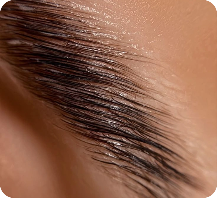 Close-up of a eyebrow with a brown color swatch on a beige background