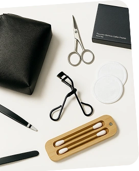 Collection of beauty tools including scissors, a black pouch, and a wooden tool on a white surface.