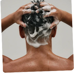 Barber applying styling product to client's hair during grooming service
