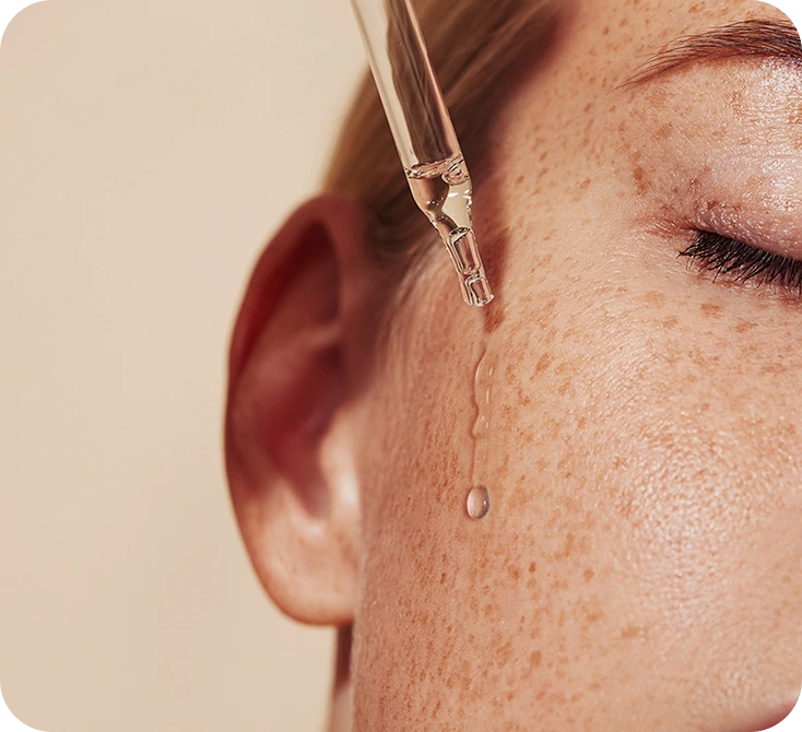 Aesthetician applying facial treatment serum with dropper during spa service